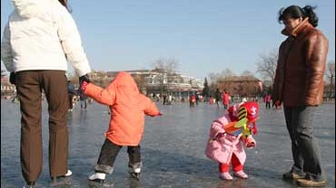 Chinese mothers play with their children on a frozen lake in Beijing 