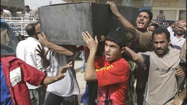 Men carry a coffin of a person killed in a rocket attack on the Khamaliya neighborhood in Baghdad 
