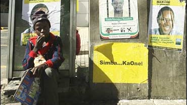 A youth sits near election posters in Harare, Zimbabwe 