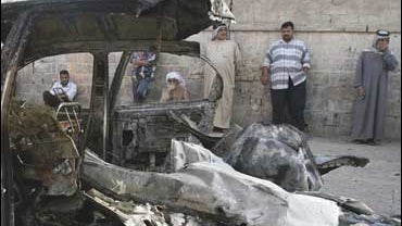 Residents look at a destroyed car in the Shiite enclave of Sadr City 