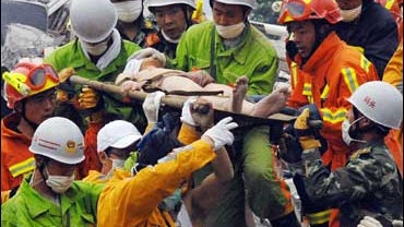 Rescuers carry a survivor on a stretcher after pulling him out of a hotel collapsed following Monday's earthquake at Yingxiu 