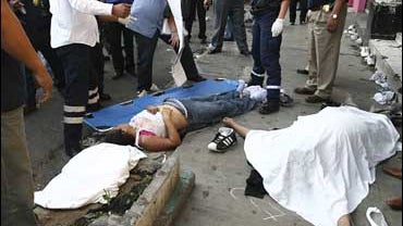 People stand around the bodies of three people outside the News Divine club in northeastern Mexico City 