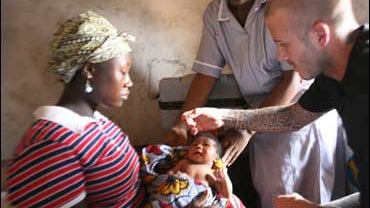 UNICEF Goodwill Ambassador David Beckham administers an oral polio vaccination to two-day-old Mariatsu, held by her mother Alice, 16, during a visit to a home for newborns run by community health workers in the town of Mangorea in Sierra Leone's Northern  