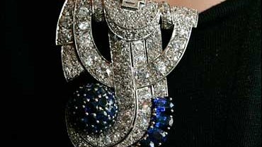 An art deco sapphire and diamond clip brooch, once owned by Sir Elton John is displayed by an employee of Bonhams in London, Tuesday Sept. 23, 2008. The "Elton John" brooch, created in 1935, is designed in the form of the initial "J" and was worn by the l 