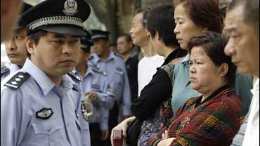 Policemen keep watch over a crowd outside Shanghai's Higher People's Court 