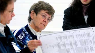 Election judges Lucy Karml and Diana Kittelson count ballots by hand over the watchful eyes of Geri Katz, a representative of Al Franken 