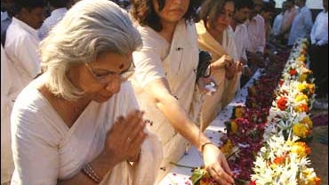 People place petals and touch the photographs of slain policemen at a prayer meeting to pay tribute to Mumbai's policemen who lost their lives in the recent terrorist attacks in Mumbai, India 
