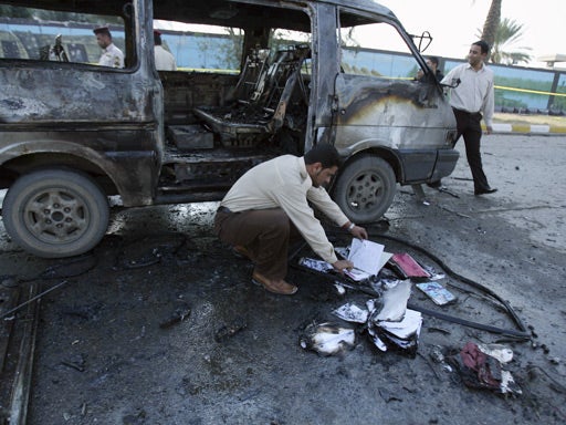 A security guard is seen looking at schoolbooks of students who were on a mini bus that was hit by a car bomb near the entrance to a police academy in Baghdad, Iraq, Monday, Dec. 1, 2008. 