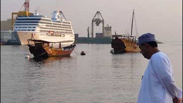 An Omani citizen views the 600-foot long M/S Nautica, left, as it sails near traditional Omani boats and prepares for a daylong port stop in the Omani capital of Muscaton Dec. 3, 2008. Passengers on the luxury cruise liner attacked by pirates in the dange 