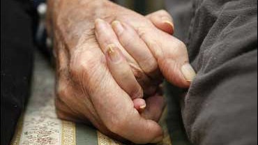Elderly couple holds hands 