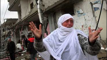 A Palestinian woman gestures as others check the damage of their destroyed houses after an Israeli missile strike at Rafah refugee camp, southern Gaza Strip 