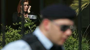 A student is seen behind a policeman talking on her phone inside a state vocational training college in western Athens, Greece, where a 18-year-old student shot and injured a fellow student and two passers-by before fatally shooting himself in the head on 