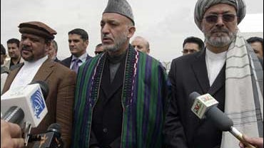 Afghan President Hamid Karzai, center, speaks to media as his first vice president Mohammad Qasim Fahim, left, and his second vice president Karim Khalili are seen with him following his registration at the election commission office in Kabul, Afghanistan 