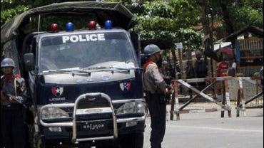 Riot police officers stand guard at a road block naear the Insein Prison in northern suburb of Yangon Tuesday, May. 19, 2009. 