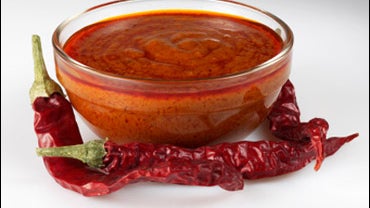 A bowl of chilli sauce surrounded by dried chillies 
