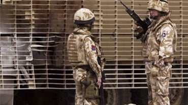 British soldiers stand guard next to their armored vehicle, after it was hit by a roadside bomb in Basra, Iraq, Friday, Feb. 27, 2009. No casualties were reported, Iraqi police said. 