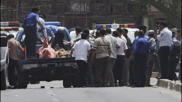 Iraqi police load victims killed in a bank robbery into a truck in central Baghdad, Iraq, Tuesday, July 28, 2009. Gunmen killed several security guards Tuesday during an early morning robbery at a bank in central Baghdad, an attack that appears to be the  