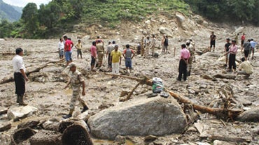 Rescue workers and volunteers stand amid the debris after a landslide at Pithoragarh district in Uttarakhand state, India, Saturday, Aug. 8, 2009. 