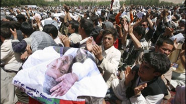 An Afghan man uses a poster of Afghan President Hamid Karzai, who is also a presidential candidate in the upcoming presidential election during an election campaign in support of Karzai in Bamiyan province, west of Kabul, Afghanistan, Sunday, Aug. 16, 200 