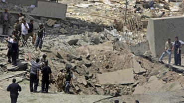 Iraqi security forces inspect a crater caused by a massive bomb attack on the Foreign Ministry 