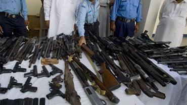 A Pakistani police officer inspects confiscated weapons display for media at a police station in Islamabad, Pakistan on Saturday, Sept. 19, 2009. 