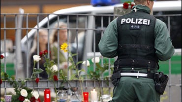 A policeman is seen next to flowers and candles in front of the Carolinum school in Ansbach, near Nuremberg, southern Germany on Friday, Sept. 18, 2009. An 18-year-old armed with an ax, knives and Molotov cocktails attacked his high school injuring eight  
