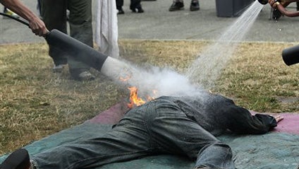 Safety monitors put out a fire set on the clothes of a student at the International Stunt School in Seattle, Monday, Aug. 10, 2009. Despite the current recession, students at the school pay thousands of dollars for training in hopes of starting new career 