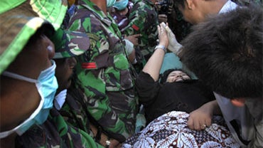 A survivor, Suci Ravika Wulan Sari, high-fives an Indonesian rescue worker as she was pulled out of a fallen building on Friday, Oct. 2, 2009 in Padang, Indonesia, after being trapped there since Wednesday's earthquake. 
