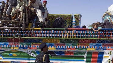A Pakistani police officer checks arriving displaced families who fled fighting between security forces and militants in Pakistani tribal area of Waziristan, at Janikhel check post near Bannu, Pakistan on Friday, Oct 23, 2009. 