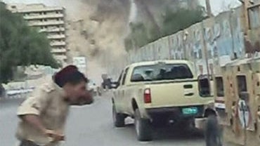 In this image from an amateur video a policeman man reacts as one of two huge car bombs explode in central Baghdad Sunday Oct 25 2009. 