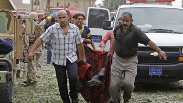 The dead body of a man is carried away from the blast scene after being killed by a massive bomb attack in Baghdad, Iraq, Sunday, Oct. 25, 2009. 
