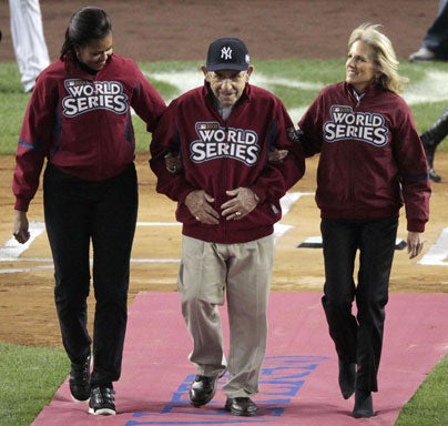 First Lady Michelle Obama, left, and Jill Biden, wife of Vice-president Joe Biden, escort former Yankee Yogi Berra to the pitchers mound 