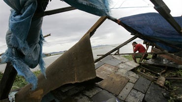 A man gestures beside his house which was toppled due to strong winds and waves bought by Typhoon Mirinae along a lakeshore town in Taytay, Rizal province, east of Manila, Philippines on Saturday, Oct. 31, 2009. 