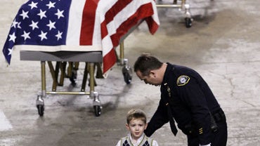 Nicholas Renninger, 3, walks in front of his father's casket, Sgt. Mark Renninger, 39, as he is escorted by an unidentified police officer toward a NASCAR racing car on display at a memorial service for four slain Lakewood police officers, Tuesday, Dec. 8 