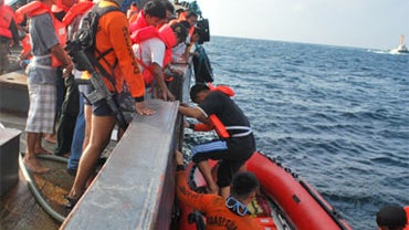 Philippine Coast Guard members assist survivors as they transferred to a rubber boat near the waters of Cavite province's Limbones island, south of Manila, Philippines, Thursday, Dec. 24, 2009. 