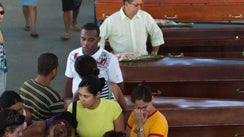 People stand by the coffins of victims of two mudslides, one in Morro da Carioca, Angra dos Reis, and another on the island of Ilha Grande, in the city of Angra dos Reis near Rio de Janeiro, Brazil, Saturday, Jan. 2, 2010. 