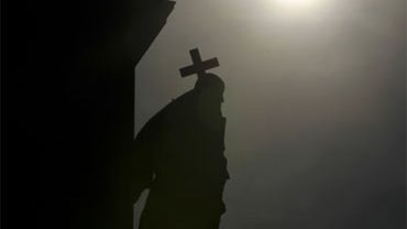 In this picture taken April 8, 2010 a stone sculpture of a man carrying a cross sits at the facade of a church in Berlin.  