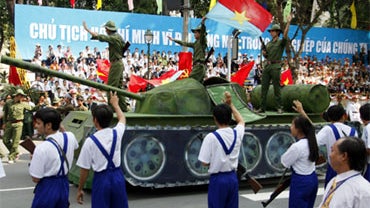 Vietnamese soldiers wave from a tank replica during a parade in Ho Chi Minh City, Vietnam on Friday April 30, 2010. 