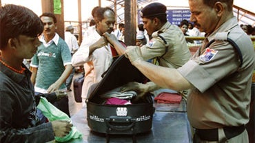 Security personnel frisk the luggage of passengers at a railway station in Delhi, India, Saturday, May 1, 2010. 