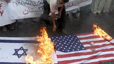 A protester burns U.S. and Israeli flags during a rally to condemn Israel's military assault on a convoy of humanitarian aid ships traveling to Gaza, Monday, May 31, 2010 in Karachi, Pakistan.  