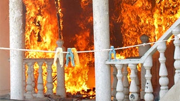 Clothes pegs hang on a rope in the foreground as an Uzbeks' residence burns after being torched by Kyrgyz men, in Jalal-Abad, Kyrgyzstan, Sunday, June 13, 2010.  