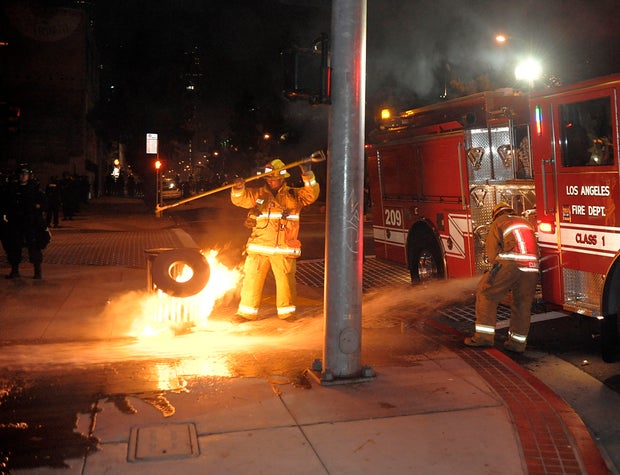 Los Angeles Fire Department firefighters extinguish a trash fire near the Staples Center in Los Angeles on Thursday, June 17, 2010. Crowds of rowdy revelers poured into the streets around Staples Center after Game 7 of the NBA finals rocking cars, setting bonfires and throwing rocks and bottles at officers.