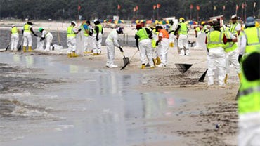 Contracted workers clean oil and tar balls from Biloxi Beach near Edgewater Mall in Biloxi, Miss., on Wednesday, June 30, 2010. (AP Photo/The Sun Herald, James Edward Bates) 