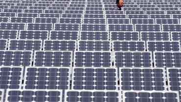 A Chinese man walks amid solar panels at a solar power facility in Wuhan city, central Chinas Hubei province, March 19, 2010. 