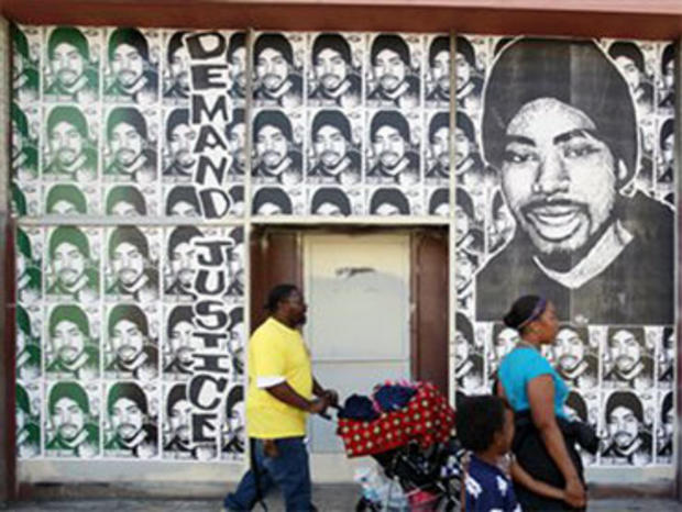 A Family Walks by Posters of Oscar Grant (AP) 