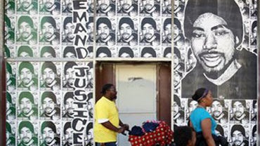 A Family Walks by Posters of Oscar Grant (AP) 