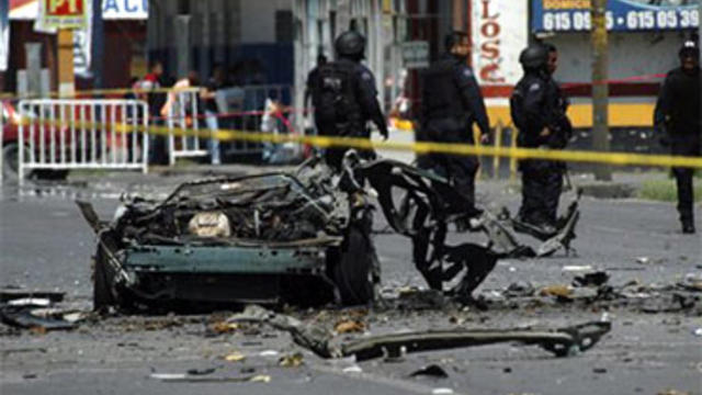 The remains of a vehicle are cordoned off in a street in the northern border city of Ciudad Juarez, Mexico, Friday July 16, 2010. Mexican investigators ran forensic tests to determine whether drug gangs used a car bomb in an attack on police patrol trucks 