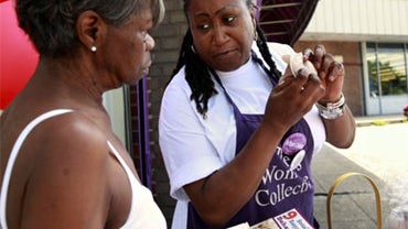 Charlene Cotton, right, demonstrates how to use the female condom outside The Women's Collective in Washington, July 21, 2010. Community groups are handing out 500,000 female condoms in the nation's capital to fight an HIV epidemic. 