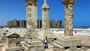 With a five star hotel in the background, a man walks by restored Roman pillar tombs of the ancient city of Leukaspis a well known Greco-Roman port overlooking the Mediterranean Sea at the costal resorts of Marina, Egypt Sunday, Aug. 29, 2010. Today, it's 
