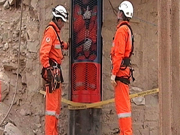 this image taken from a video and released by the government of Chile on Monday Oct. 11, 2010, rescue workers look on as a colleague gives a thumb up from inside the rescue capsule while performing a dry run test for the eventual rescue of the 33 miners t 